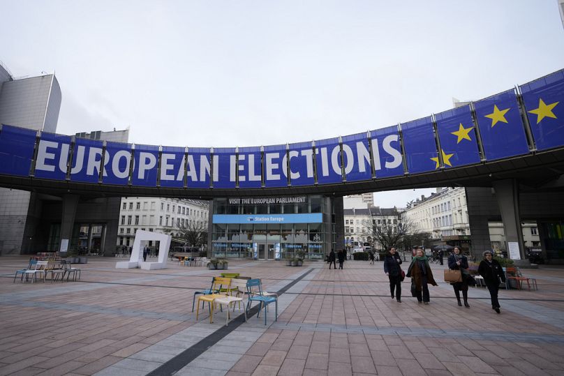 People walk under a banner advertising the European elections outside the European Parliament in Brussels, January 2024