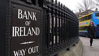 A woman walks past the offices of Bank of Ireland Monday Feb 20 2012.