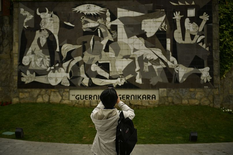 A visitor takes photos of a wall decorated with the famous Pablo Picasso's ''Guernica'' painting in Basque Spain