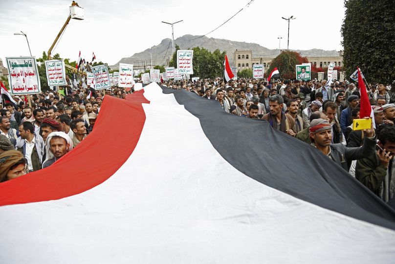 Apoiantes Houthis cantam slogans segurando cartazes onde se lê "Morte à América, Morte a Israel", enquanto participam num comício em Sanaa, em março passado.