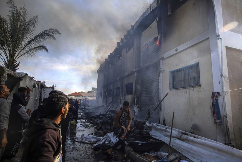 Palestinians try to extinguish a fire at a building of an UNRWA vocational training center which displaced people use as a shelter, after being targeted by Israeli tank