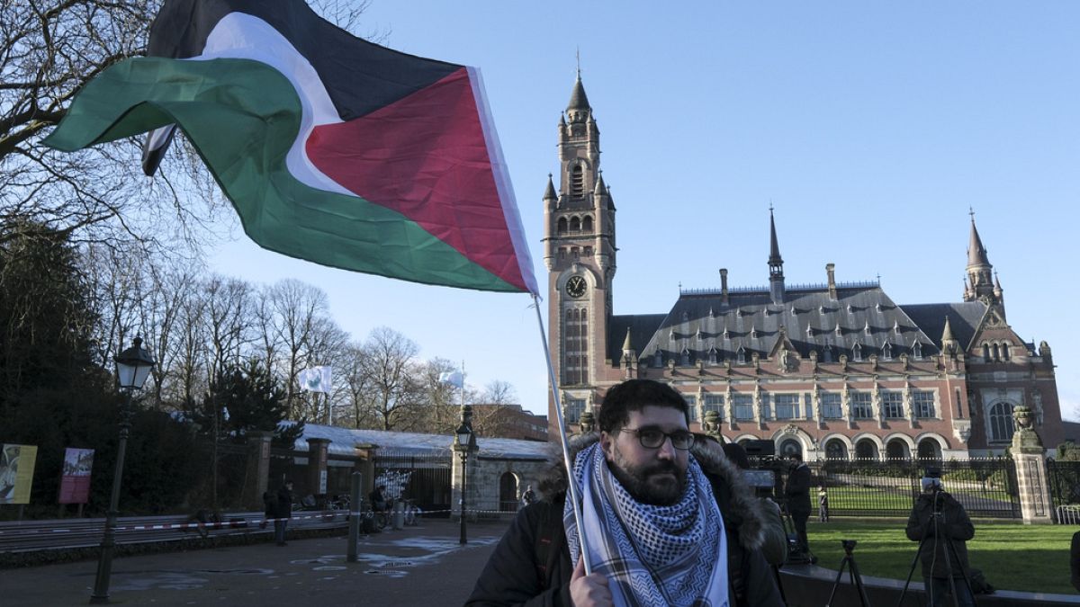 Διαδηλωτής με τη σημαία της Παλαιστίνης έξω από το Διεθνές Δικαστήριο της Χάγης