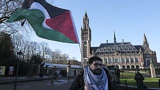 Διαδηλωτής με τη σημαία της Παλαιστίνης έξω από το Διεθνές Δικαστήριο της Χάγης