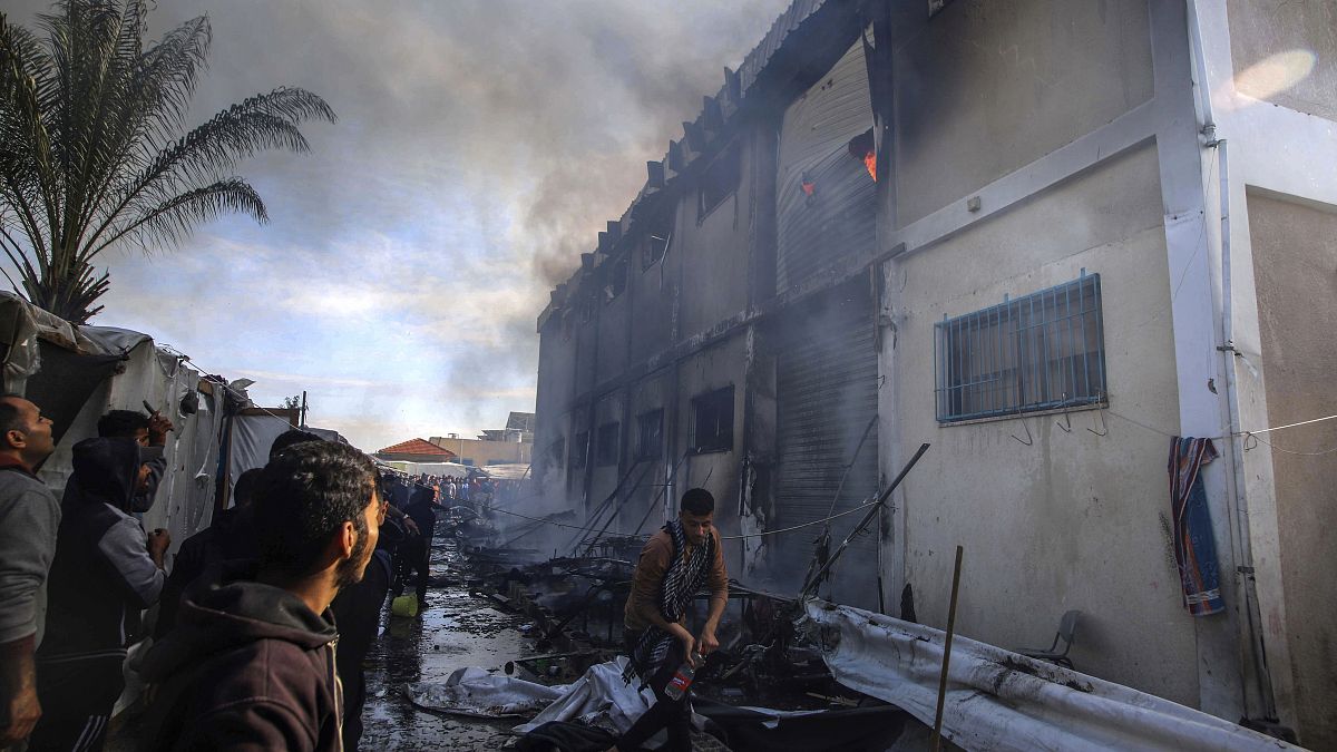 Палестинцы тушат пожар во временном убежище БАПОР в Хан-Юнисе, после израильского обстрела, 24 января 2024 г.