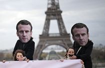 Activistas con máscaras de Emmanuel Macron colocan sus manos sobre mujeres amordazadas durante una manifestación en París, el 24 de noviembre de 2023