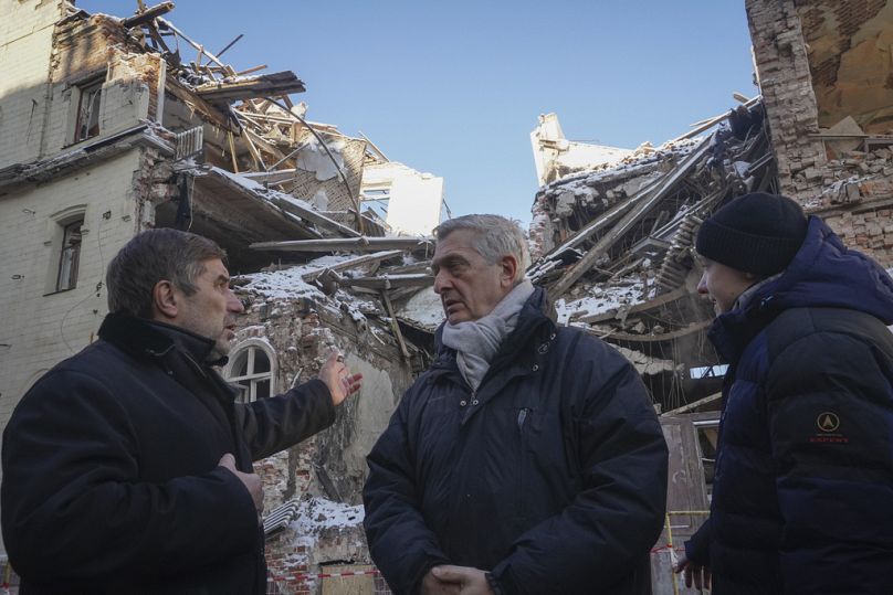 United Nations High Commissioner for Refugees Filippo Grandi, centre, listens to a local resident as he visits sites of recent bombings in Kharkiv, Ukraine, Monday, Jan. 22