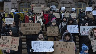 People hold posters reading "Return defenders of Mariupol", "Free Azov", and others, during a demonstration in central Kyiv, Ukraine, Sunday, Dec. 3, 2023. 