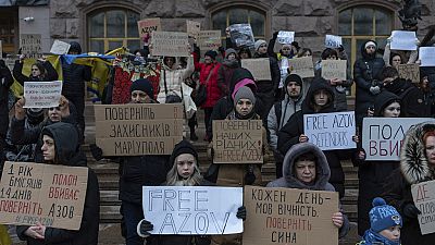 People hold posters reading "Return defenders of Mariupol", "Free Azov", and others, during a demonstration in central Kyiv, Ukraine, Sunday, Dec. 3, 2023. 