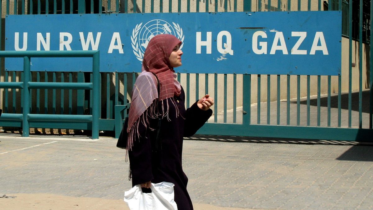 Una donna cammina davanti alla sede dell'UNRWA a Gaza