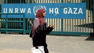 Una donna cammina davanti alla sede dell'UNRWA a Gaza