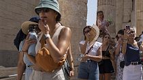 سائحون يزورون تل الأكروبوليس القديم خلال موجة الحر في أثينا، اليونان، في 21 يوليو 2023