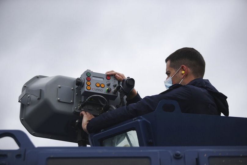 A Greek police officer operates a long range acoustic device, LRAD, during a patrol alongside the Greek - Turkish border near the town of Feres, May 2021