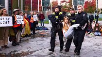Police officers carry away an activist of the 'Letzte Generation' during a climate protest in Berlin, 31 October 2023.