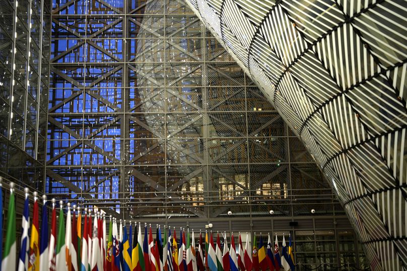 Des drapeaux de l'Union européenne sont alignés sur un tapis rouge dans le hall d'entrée lors d'une réunion dans le bâtiment du Conseil européen à Bruxelles, décembre 2023.