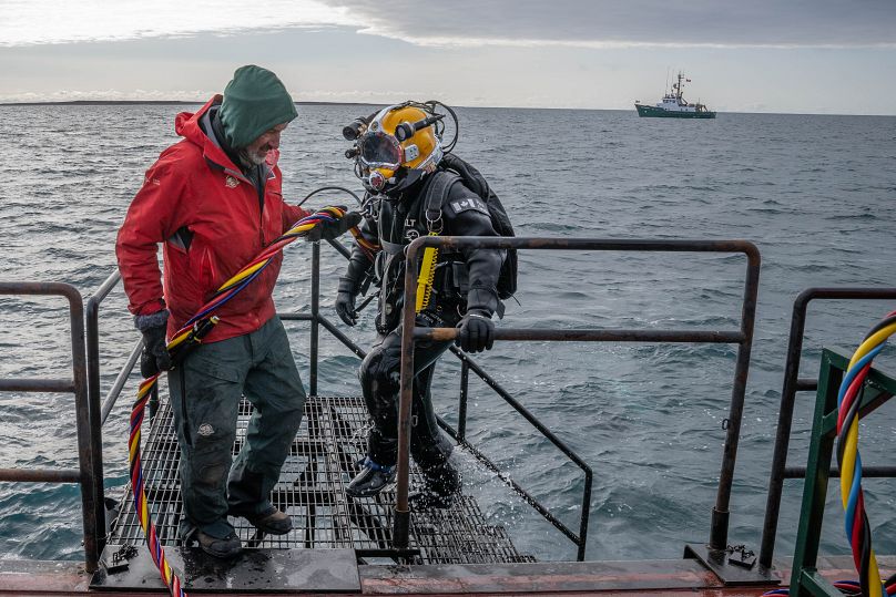 Техник по подводной археологии Тодд Стакенвичус возвращается на вспомогательную баржу после погружения на HMS Erebus, на фоне судна David Thompson, 6 сентября 2023 года.