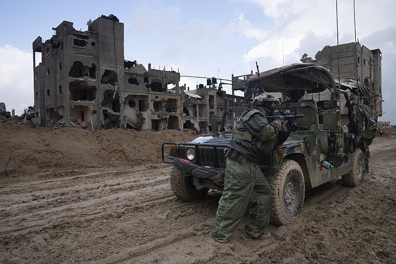 Izraeli katona őrt áll egy szétlőtt épület előtt a Gázai övezetben