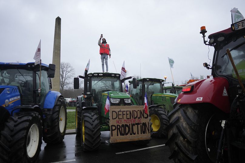 A farmer stands atop a tractor as farmers block a roundabout in Fontainebleau, south of Paris.