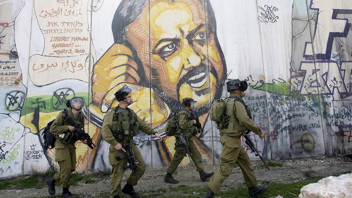 جنود إسرائيليون بجانب جدارية للأسير مروان البرغوتي في رام الله 