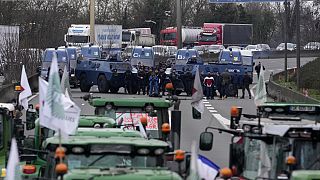 Auf einer französischen Autobahn stehen sich Landwirte mit Traktoren und Polizisten mit gepanzerten Fahrzeugen gegenüber.