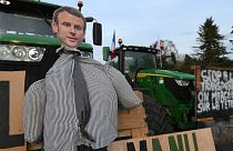 Un'effigie del presidente francese Emmanuel Macron viene vista su un trattore mentre gli agricoltori manifestano su un'autostrada.
