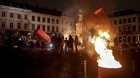 Farmers get warm around a fire as they gather for a protest outside the European Parliament ahead of an EU summit in Brussels.