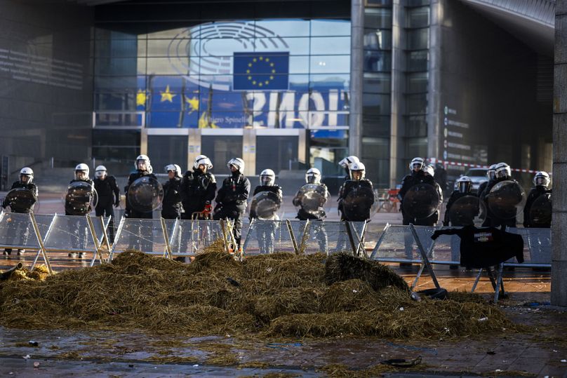 Anti riot police officers stand guard in a closed security area outside the European Parliament during a protest by farmers as European leaders meet for an EU summit