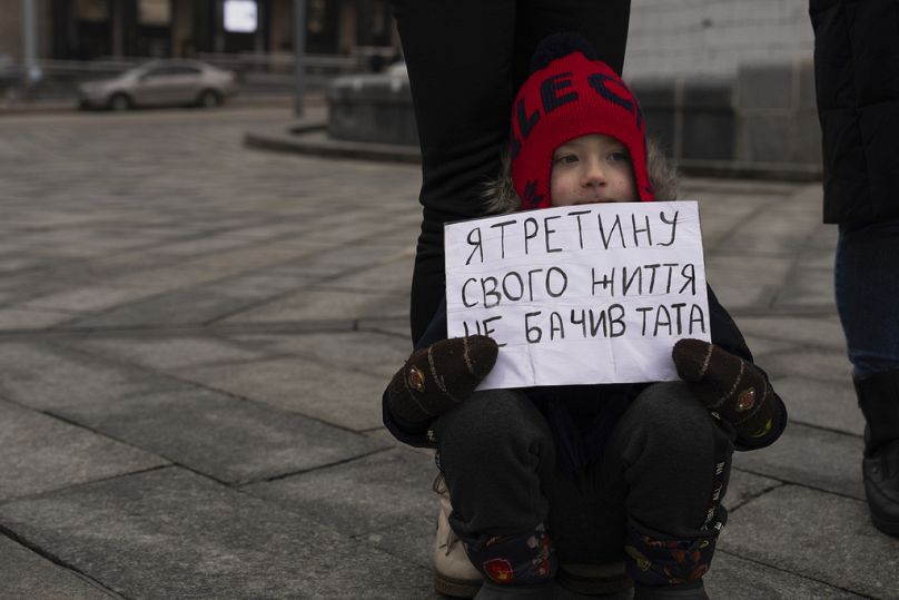 Matvii, 4, holds a poster reading "I didn't see my father for a third part of my life", while attending a rally on Independence square in Kyiv, January 2024