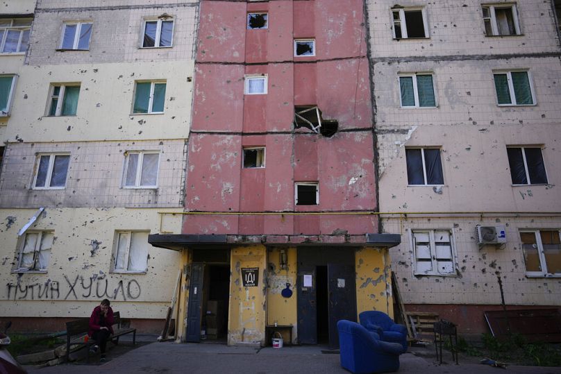 Местный житель сидит у подъезда поврежденного обстрелом дома в Ирпене, 24 мая 2022 года