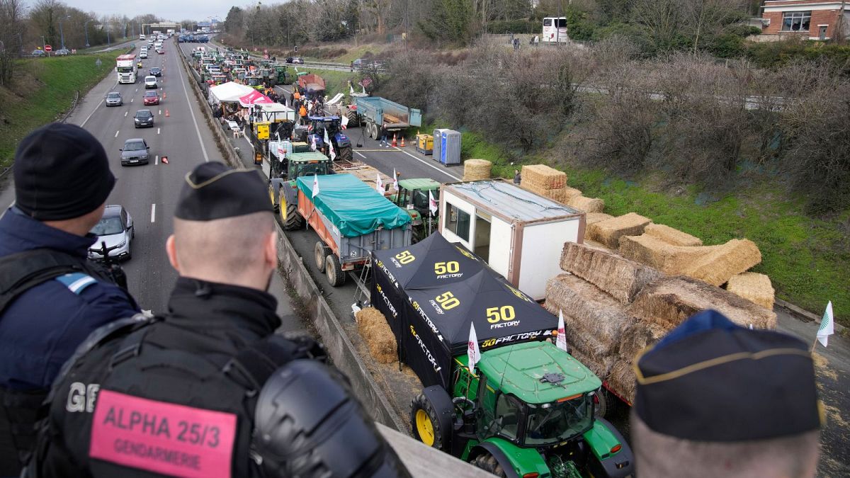 پلیس فرانسه در حال نظاره کردن مسدود شدن یک بزرگراه منتهی به شهر پاریس توسط کشاورزان معترض در روز ۳۱ ژانویه ۲۰۲۴