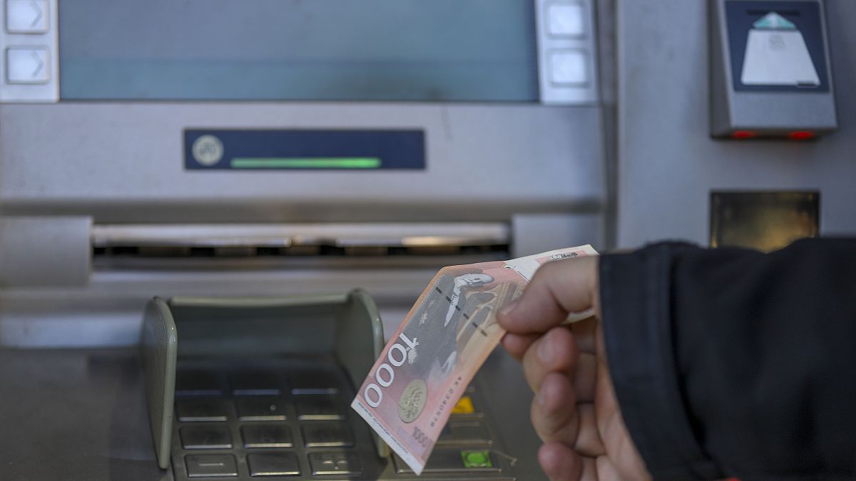 Szerb dinárt vesz fel egy férfi a koszovói Mitrovicában egy bankautomatából 2024. január 31-én.