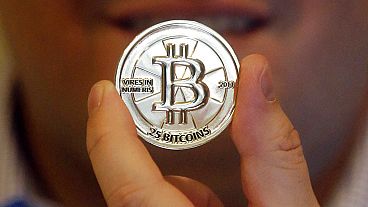  Sur cette photo prise le 3 avril 2013, un homme tient un jeton portant le symbole d'une crypto-monnaie dans son magasin de Sandy, dans l'Utah. 