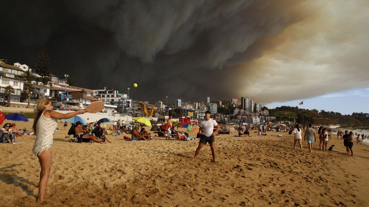 Rauchwolken über Urlaubern, die am Strand in Viña del Mar Paddelball spielen, 2. Februar 2024.