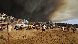 Rauchwolken über Urlaubern, die am Strand in Viña del Mar Paddelball spielen, 2. Februar 2024.