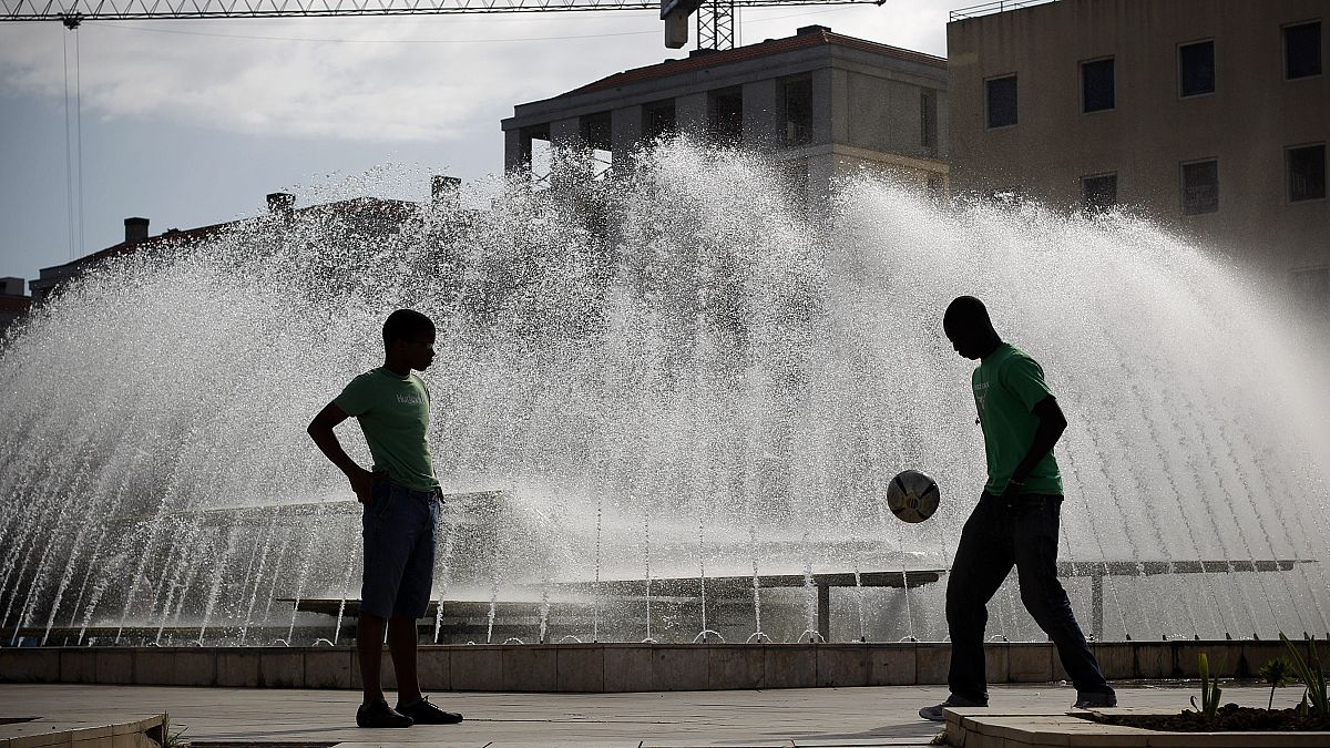 FILE. Two young men, seen in silhouette, play with a soccer ball at Lisbon's Martim Moniz