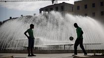 FILE. Due giovani, visti in silhouette, giocano con un pallone da calcio al Martim Moniz di Lisbona.