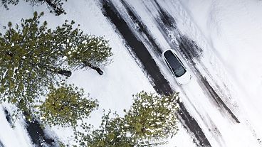 A Tesla Model Y driving through snowy winter conditions.