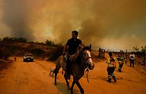 Un residente fugge da un incendio boschivo in corso a Vina del Mar, in Cile, sabato 3 febbraio 2024.