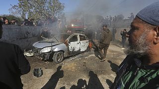 Ciudadanos palestinos observan cómo arde un coche tras ser alcanzado por un dron israelí en Rafah, en el sur de la Franja de Gaza, el domingo 4 de febrero de 2024.