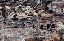 Locals clean the rubble of burnt-out houses after forest fires reached their neighborhood in Vina del Mar, Chile, Sunday, Feb. 4, 2024.