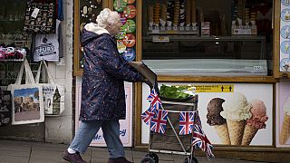 A older woman pushes a trolley decorated with Union Jack flags in Windsor. May 5, 2023.