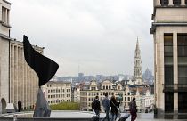 Gente paseando con equipaje con la ciudad de Bruselas como telón de fondo