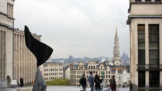 Persone che camminano con i bagagli con la città di Bruxelles come sfondo