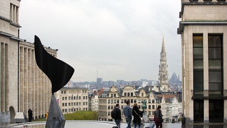 People walk with luggage with the city of Brussels as a backdrop (file photo)