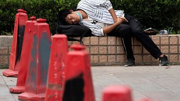 رجل يخفض قناعه وهو يغفو في شوارع بكين