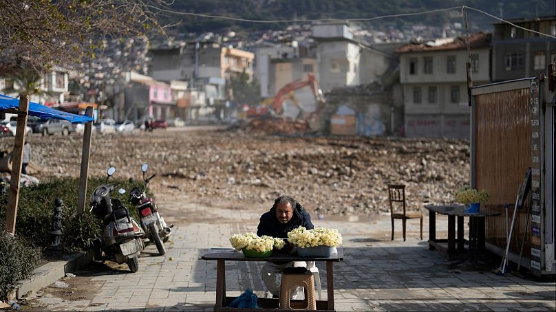 رجل يعرض زهورا للبيع بجوار بقايا مبان مدمرة وسط مدينة أنطاكيا