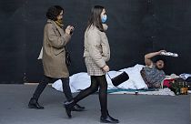 A homeless man gestures as women walking in Paris