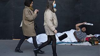 A homeless man gestures as women walking in Paris