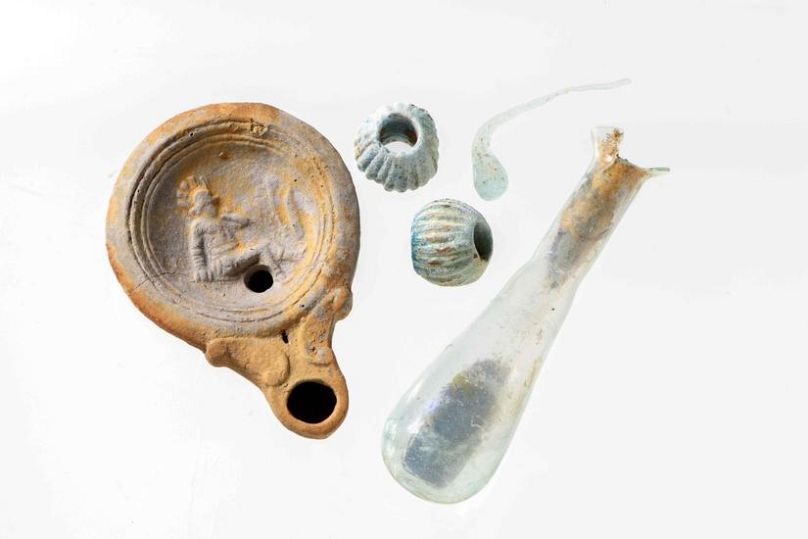 Lámpara romana, frasco de vidrio y perlas del sitio del descubrimiento.