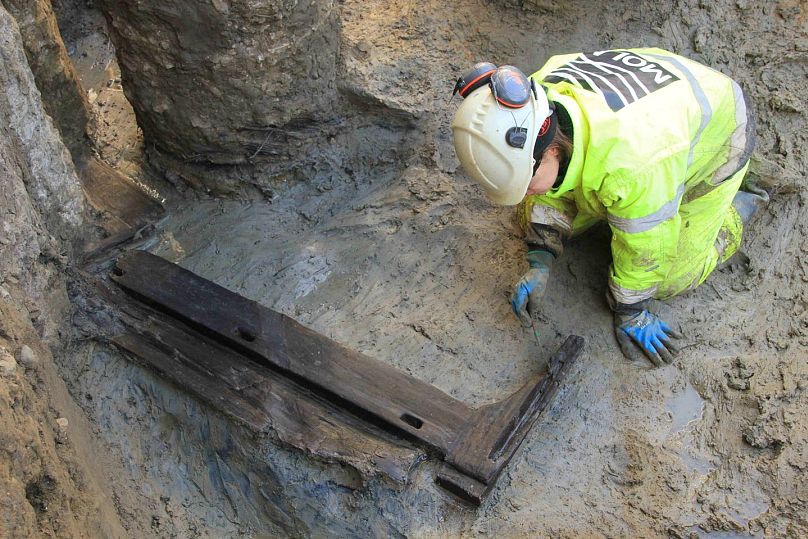 Bir arkeolog Londra'da keşfedilen ahşap yatağın etrafında çalışıyor
