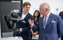 Britain's King Charles looks at a wearable device for cattle to neutralise their methane emissions in real time created by design group Zelp.